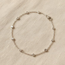 Silver bracelet with disc beads on a beige fabric background