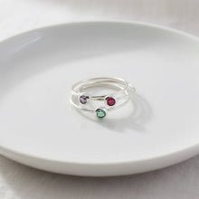 Three silver rings with colored stones on a white plate
