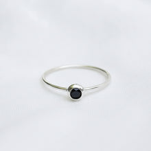 Silver ring with a black gemstone on a white background