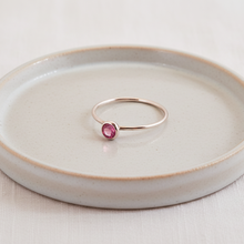 silver ring with a pink gemstone on a ceramic plate